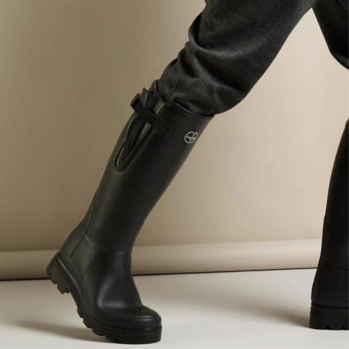 Person stepping forward wearing black wellies on a neutral background