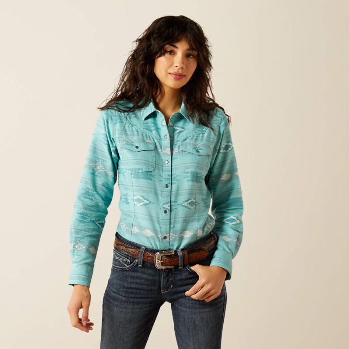 Woman wearing a turquoise patterned shirt and jeans on a beige background
