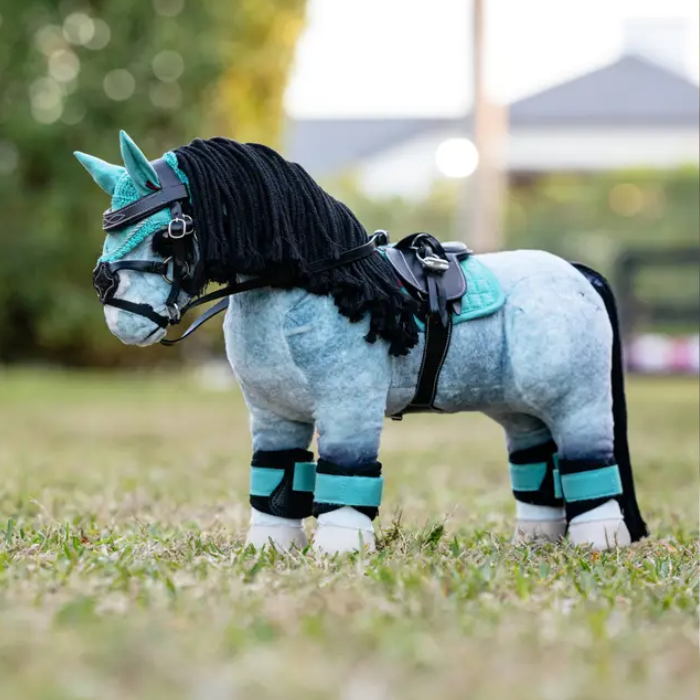 Plush toy horse with blue and black details standing on grass