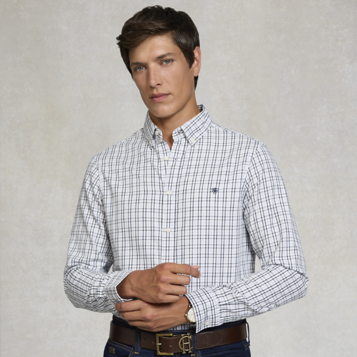 Man wearing a plaid shirt with a visible brand logo against a plain background