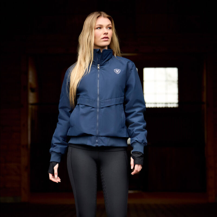 Woman wearing a blue jacket with a logo on a dark background
