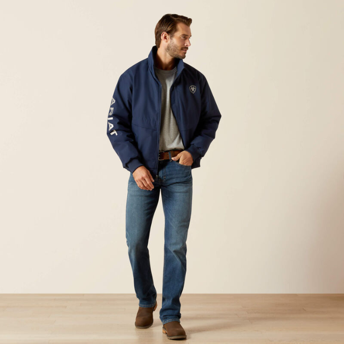 Man wearing a navy jacket with a brand logo, standing against a plain background