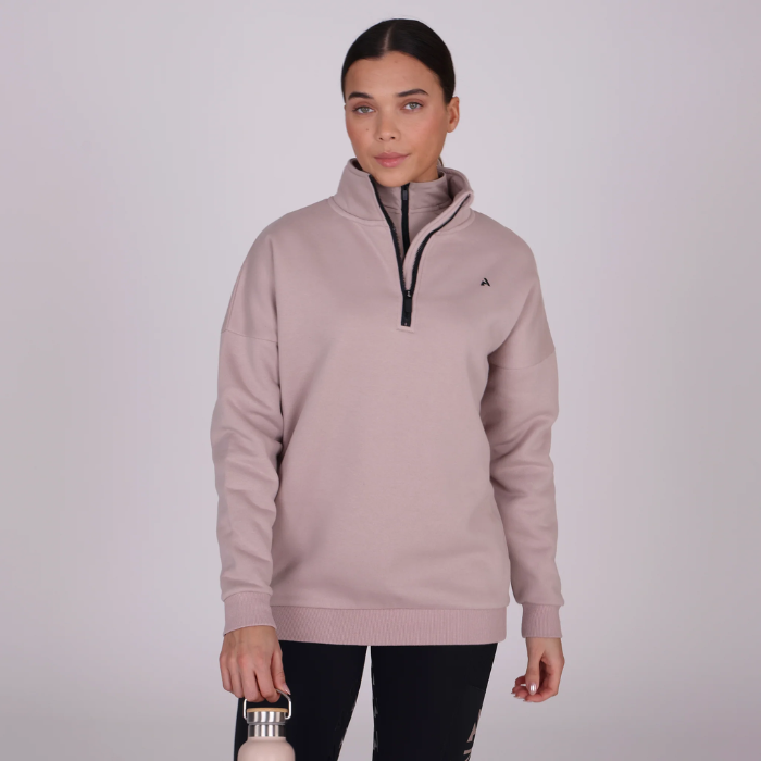 Woman wears a beige sweatshirt against a grey background
