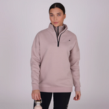 Woman wears a beige sweatshirt against a grey background