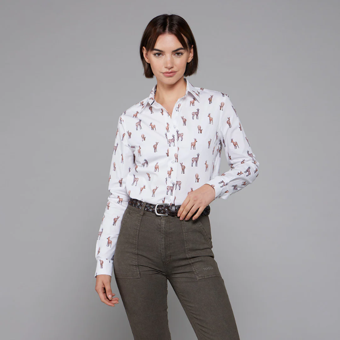 Woman wearing a white shirt with deer pattern and dark trousers on a grey background