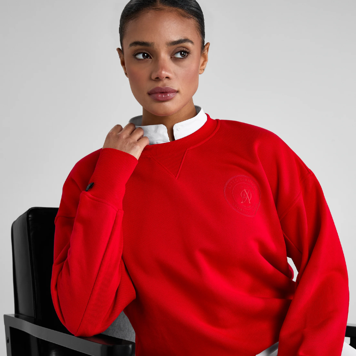Woman wears a red sweatshirt on a grey background