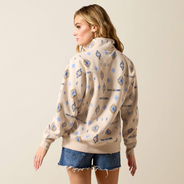 Woman wears a light beige sweatshirt with western pattern on a plain background