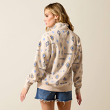Woman wears a light beige sweatshirt with western pattern on a plain background