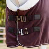 Close-up of a brown horse rug with straps and buckles, featuring the brand 'LeMieux'.