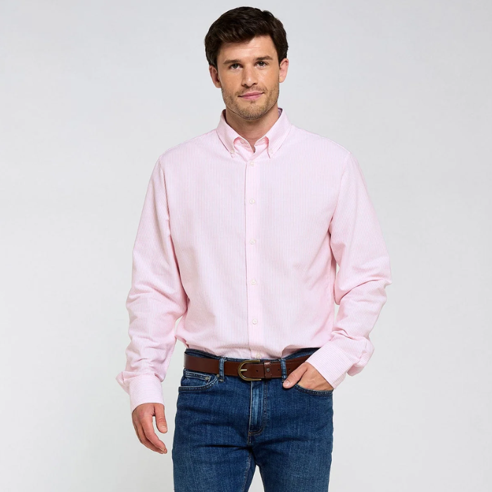 Man wearing a pink shirt and blue jeans on a pale background