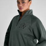 Woman wears a green sweatshirt with AD logo on a grey background