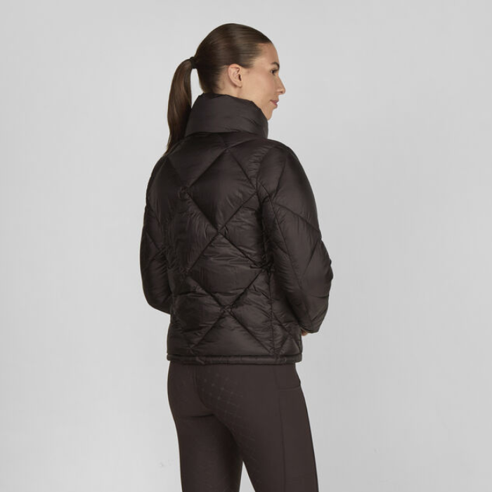 Woman wearing a dark quilted jacket on a light grey background