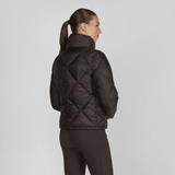 Woman wearing a dark quilted jacket on a light grey background