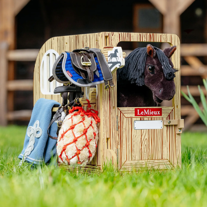 Horse stable toy with horse figure, saddle, and bridle on grass