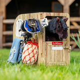 Horse stable toy with horse figure, saddle, and bridle on grass