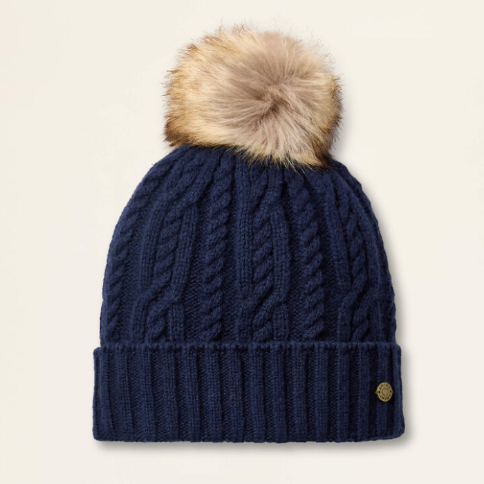 Navy blue knit beanie with a fur pom-pom on a beige background