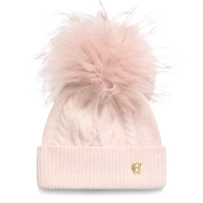 Soft pink knitted beanie hat with a fluffy bobble and gold HC hardware on a white background