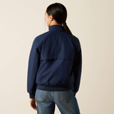 Person wears a navy bomber jacket on a beige background