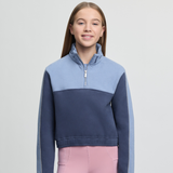 Girl wearing a two-tone blue and navy sweater with pink leggings on a light grey background