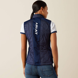 Person wearing a navy blue vest with 'Ariat' branding on the back, standing against a beige background.