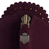 Branded zipper on a pair of purple suede boots against a white background