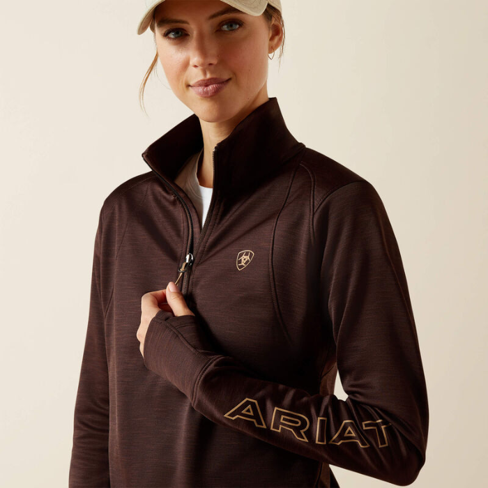 Woman wearing a brown Ariat jacket on a beige background
