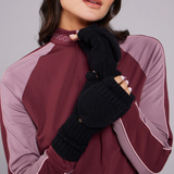 Person wearing a maroon and pink outfit with black gloves on a grey background