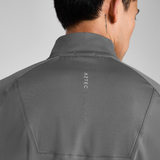 Person wearing a grey top with 'Aztec Diamond' branding on the back against a light grey background