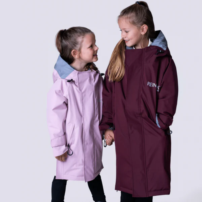 Two young girls wearing rain coats on a white background
