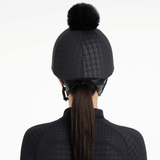 Person wears a horse riding hat with black and grey patterned cover on a white background