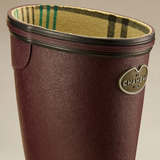 Red wellington boot with plaid lining and 'Le Chameau' logo on a beige background
