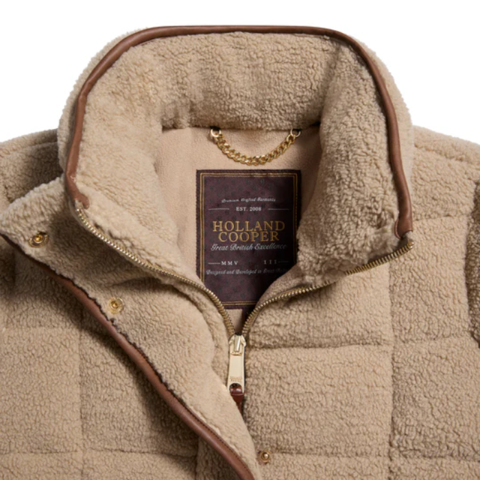 Close-up of a beige quilted jacket with a Holland Cooper label on a white background