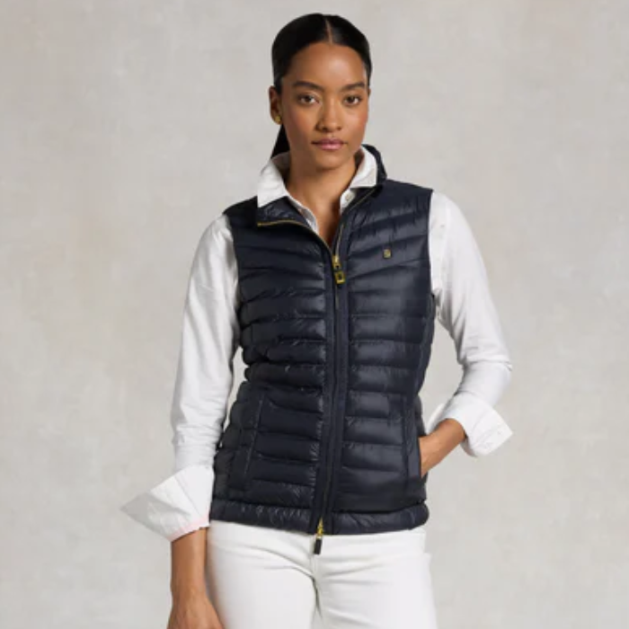 Woman wearing a navy puffer gilet over a white shirt on a plain background