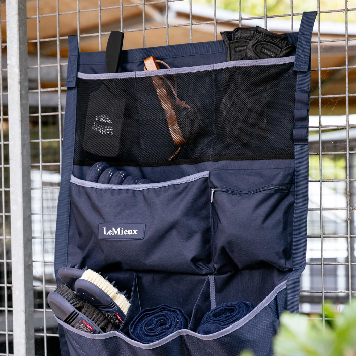 Navy blue hanging storage pockets with horse brushes and leg bandages stored on a metal frame