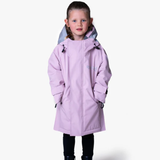 Young girl wears a light pink long rain coat against a white background