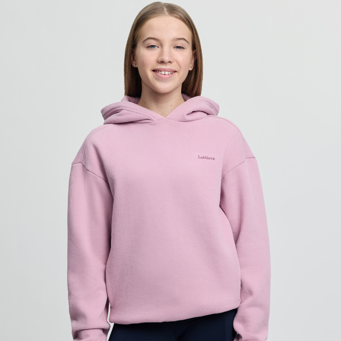 Person wearing a pink hoodie with a brand logo on a light grey background