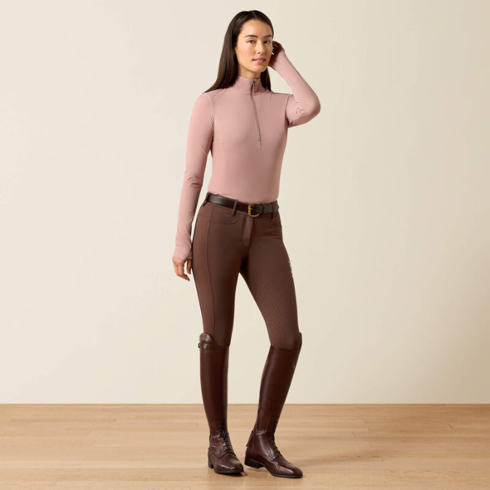 Soft pink riding top with brown leggings on a beige background