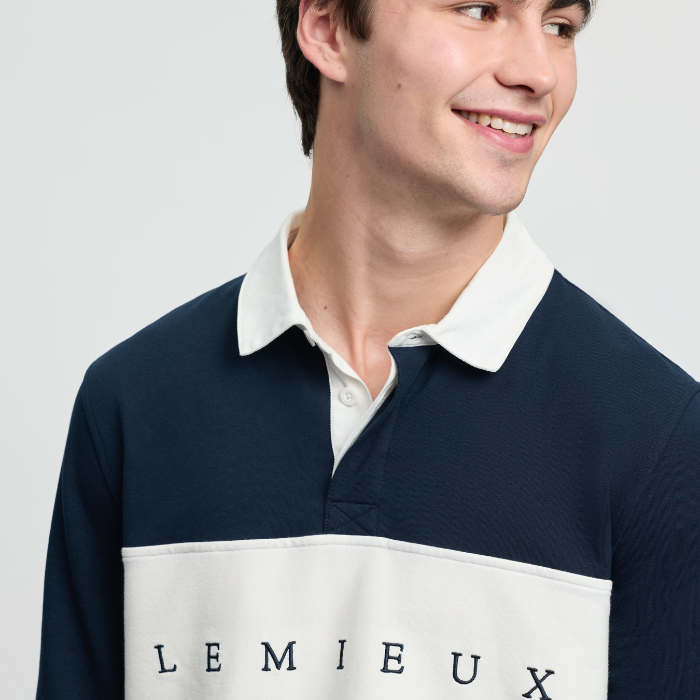 Man wearing a navy and white polo shirt with 'LEMIEUX' branding on a light grey background