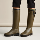Person wearing a pair of green wellington boots against a neutral background