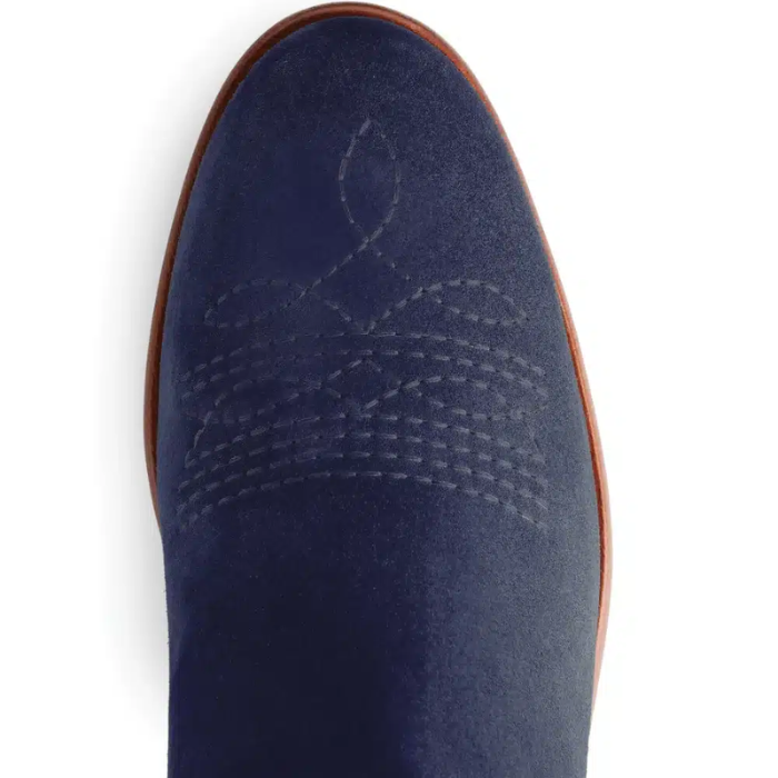 Embroidered detail on the of a blue suede boot on a white background