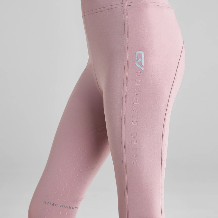 Close-up of pink riding leggings with AZTEC DIAMOND logo on a grey background