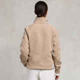 Person wearing a beige jacket with branding on a light grey background