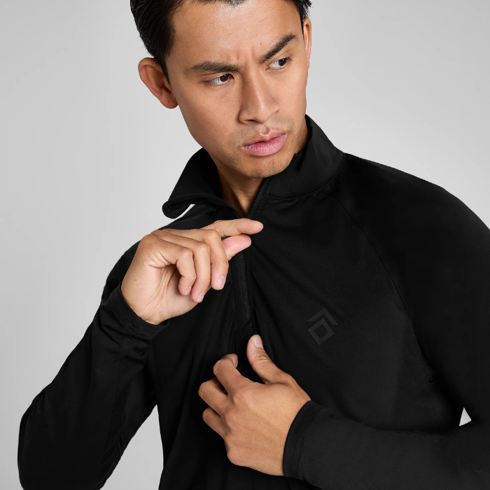 Man wearing a black long sleeved top against a grey background