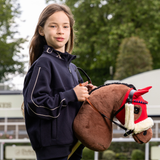 Girl holds a brown hobby horse in an outdoor setting 