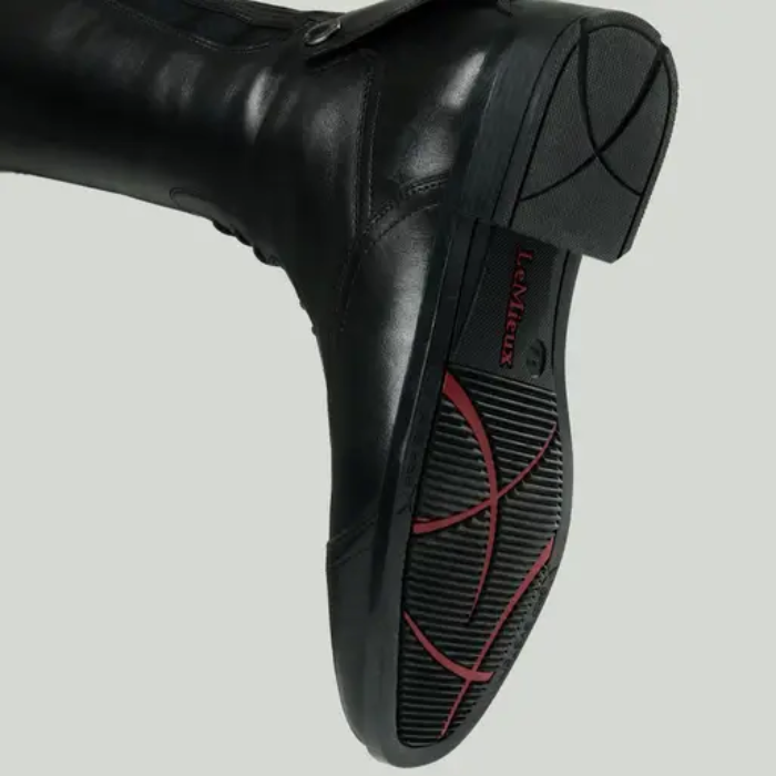 Black riding boot with a brand logo on a grey background