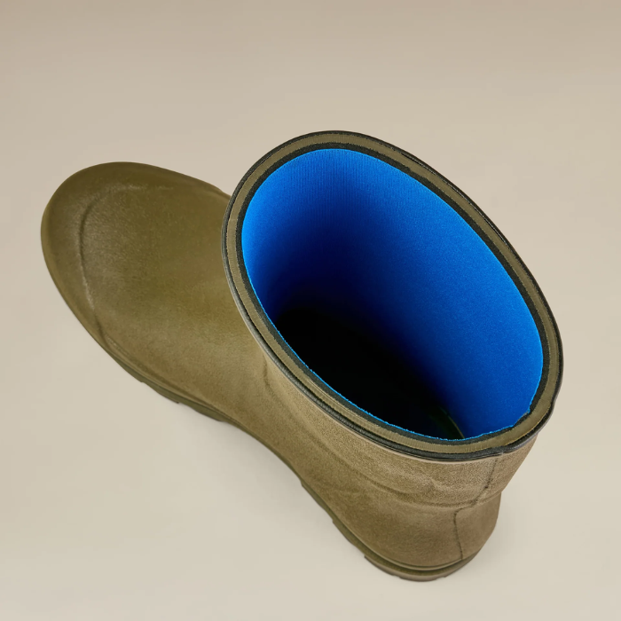 Green wellington boot with a blue lining on a beige background