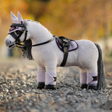 Plush toy horse with bridle and reins standing on a gravel surface.