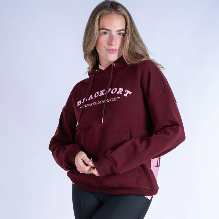 Person wearing a burgundy hoodie with 'Blackfort Equestrian Sport' text on a white background