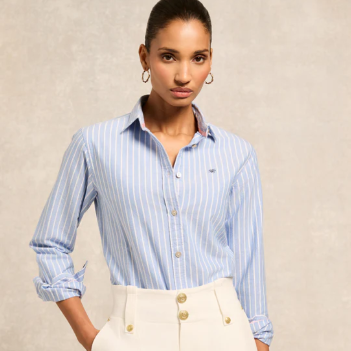 Woman wearing a light blue striped shirt with a beige background