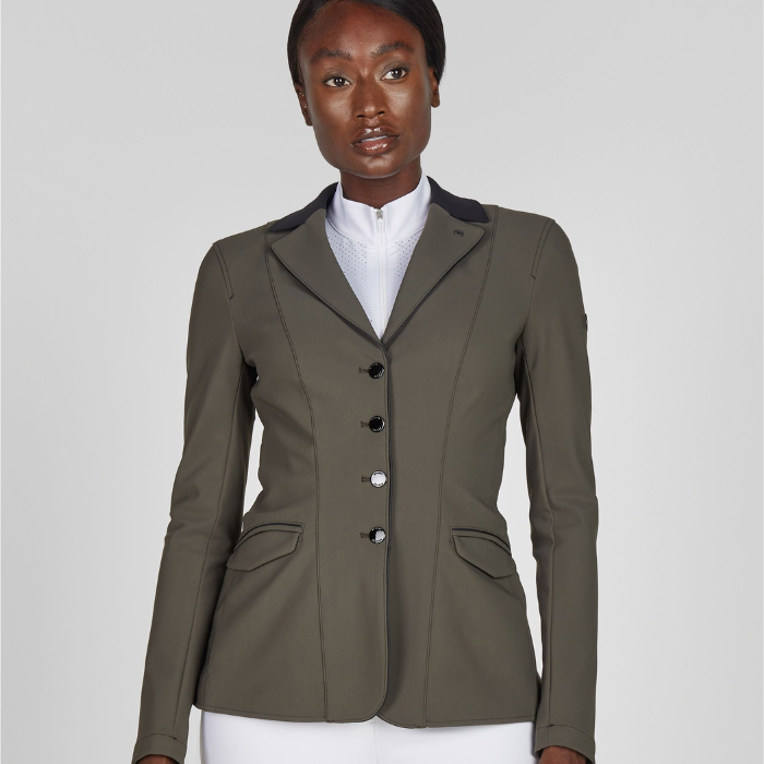 Woman wearing a green equestrian jacket on a plain background